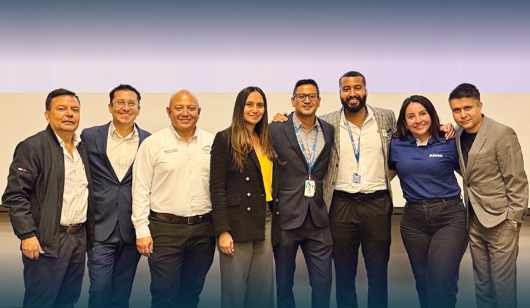 Group of eight professionals smiling for a team photo at a conference or corporate event, standing in a row together.