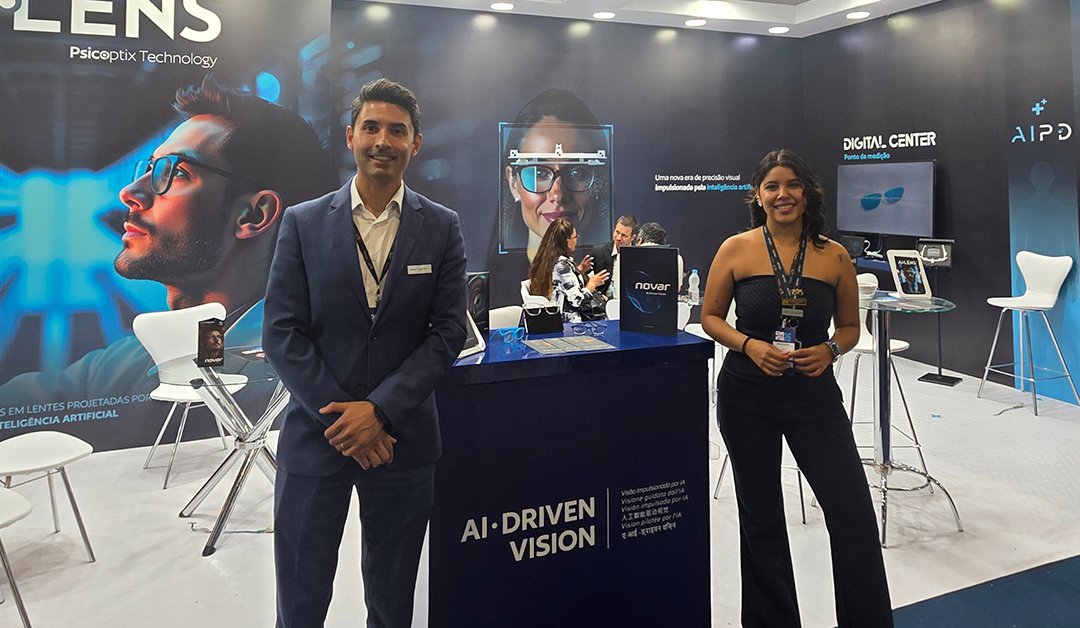 Two expo staff stand at a booth labeled AI-Driven Vision with large backdrops and a display table in a tech conference hall.