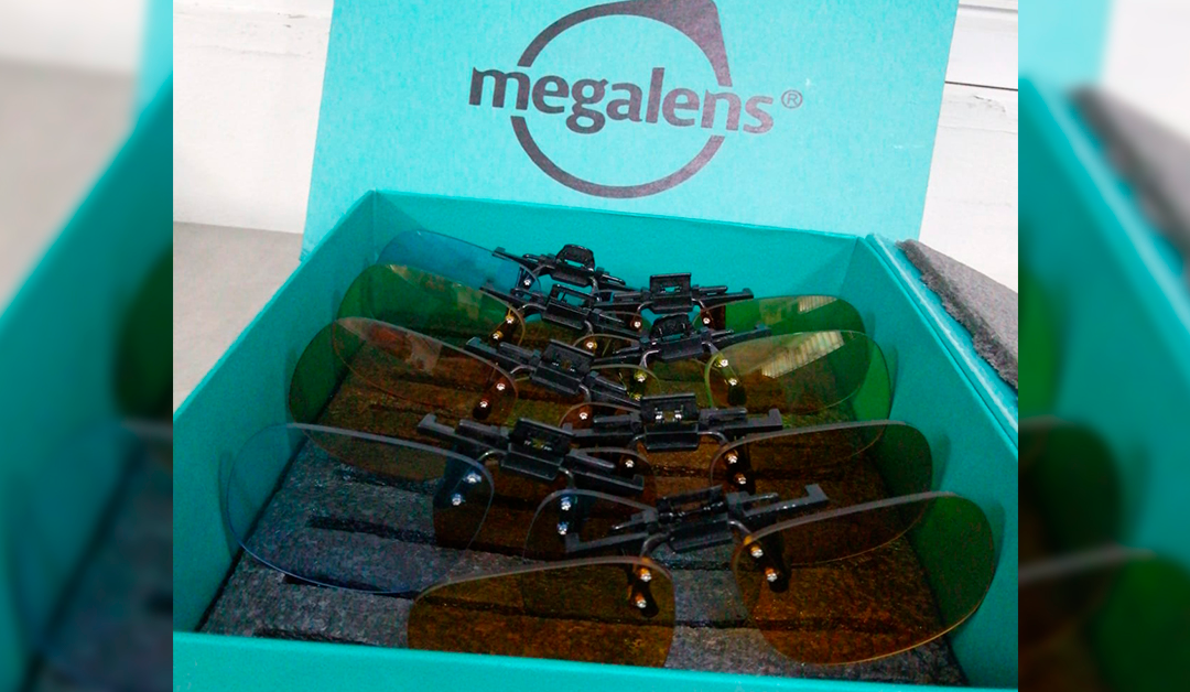 Teal box labeled 'megalens' filled with multiple curved tinted sunglass lenses and black mounting hardware.