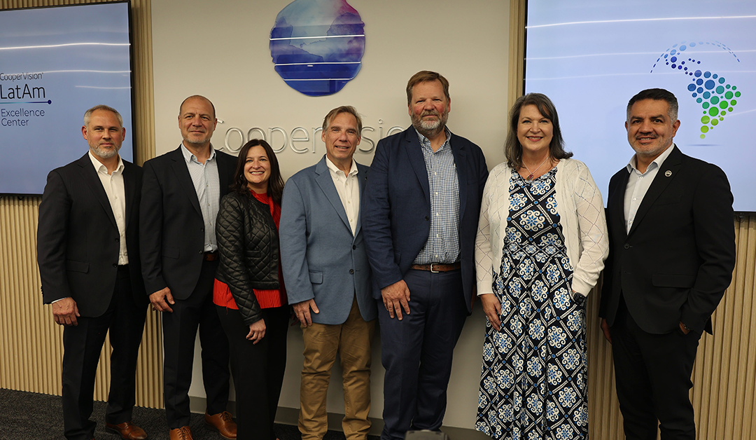 Seven professionals pose for a group photo in a corporate lobby with CooperVision LatAm signage visible behind them.