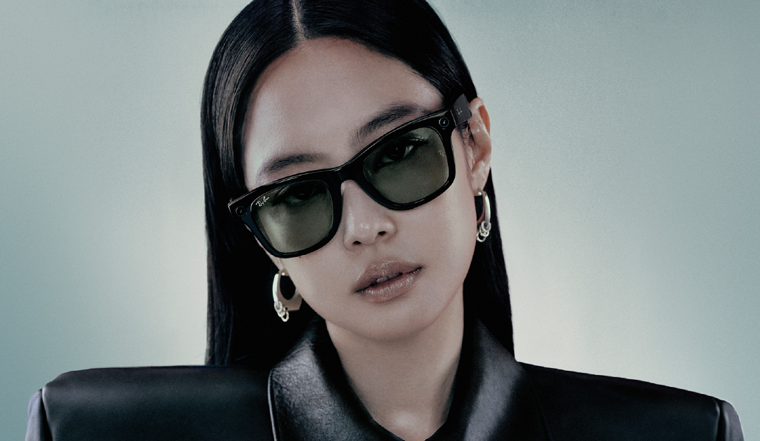 Portrait of a woman wearing black sunglasses and a black leather jacket, facing the camera with hoop earrings visible