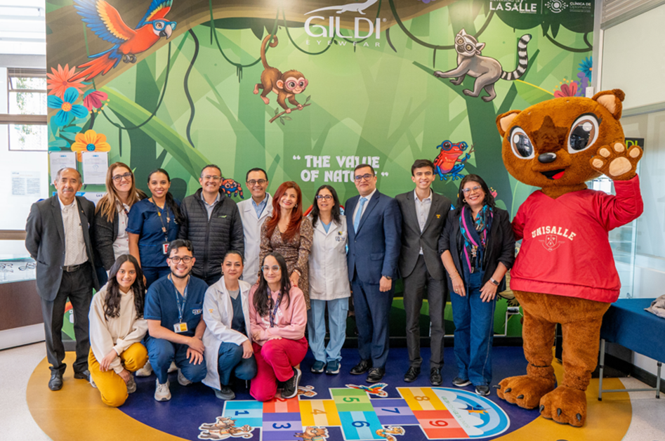 Group of adults and kids posing with a tiger mascot in a bright jungle-themed backdrop; colorful floor game visible in the foreground.