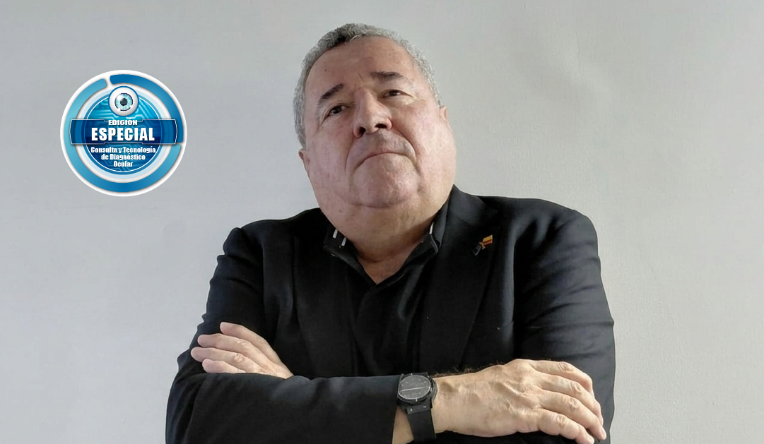 Hombre mayor con blazer negro, brazos cruzados, frente a pared gris; insignia azul de 'Edición Especial' a su izquierda.