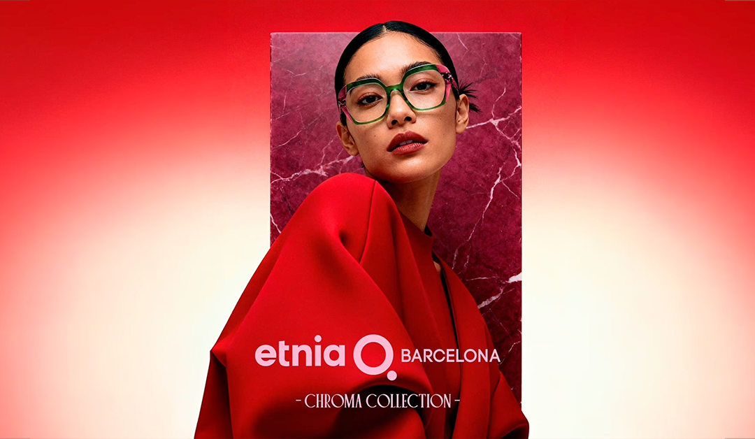 Fashion model in a red cloak with green glasses posed against a pink marble panel, showcasing Etnia Barcelona Chroma Collection.